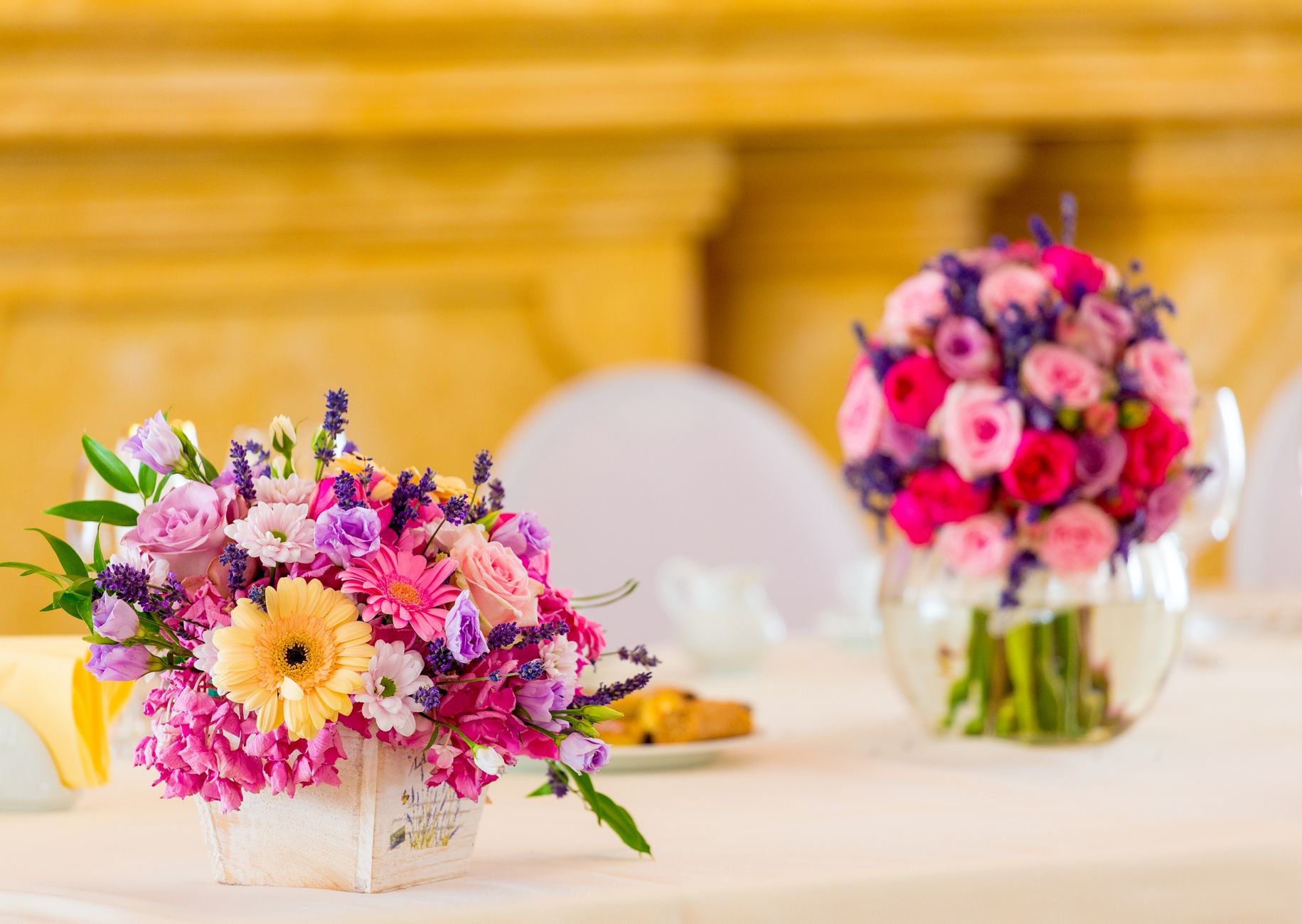 Two colorful floral centerpieces on a decorated table in a bright room