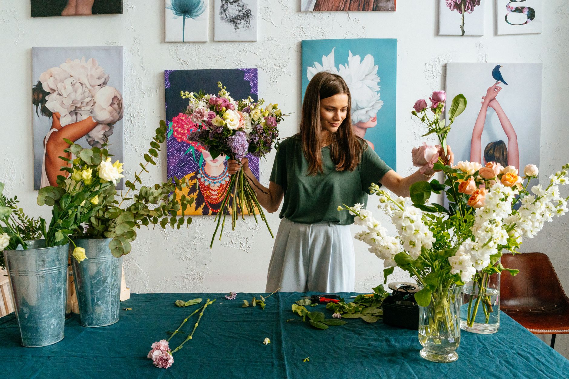A florist at a worktable arranging bouquets in a studio filled with flowers