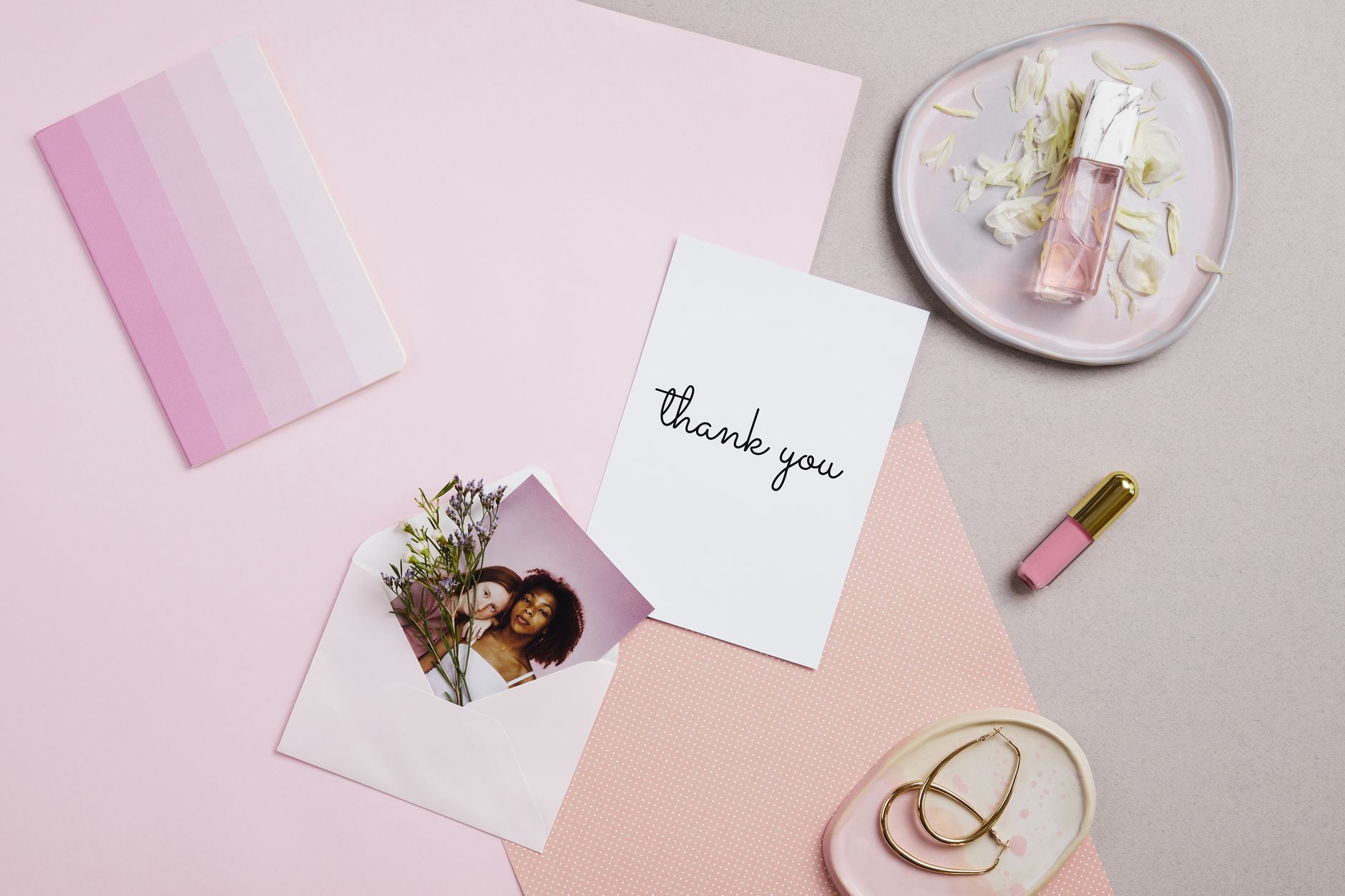 A handwritten thank you card on a flat lay surface with flower petals and keepsakes