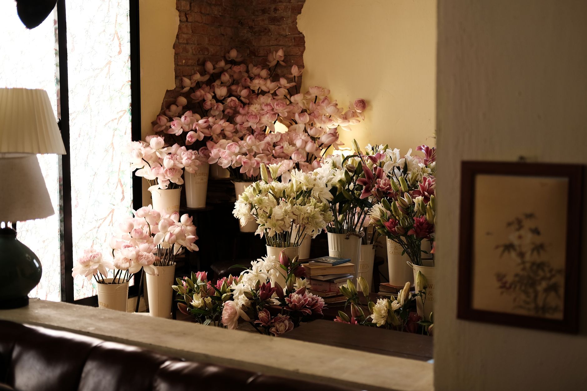 A cozy flower shop interior with vases of pink and white lilies, alstroemeria and other blooms in warm window light